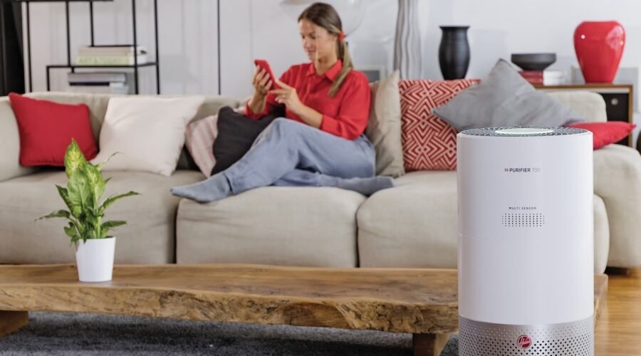 a woman sitting on a couch using a phone and Air Purifier